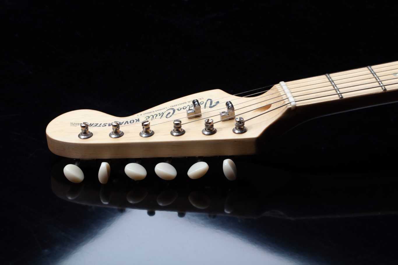 Gitarrenhals Gitarrenhals mit sechs Saitenhaltern auf schwarzem Hintergrund.