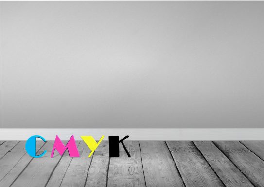 Bunte Buchstaben "CMYK" auf einem grauen Wandhintergrund und einem Holzfußboden.
