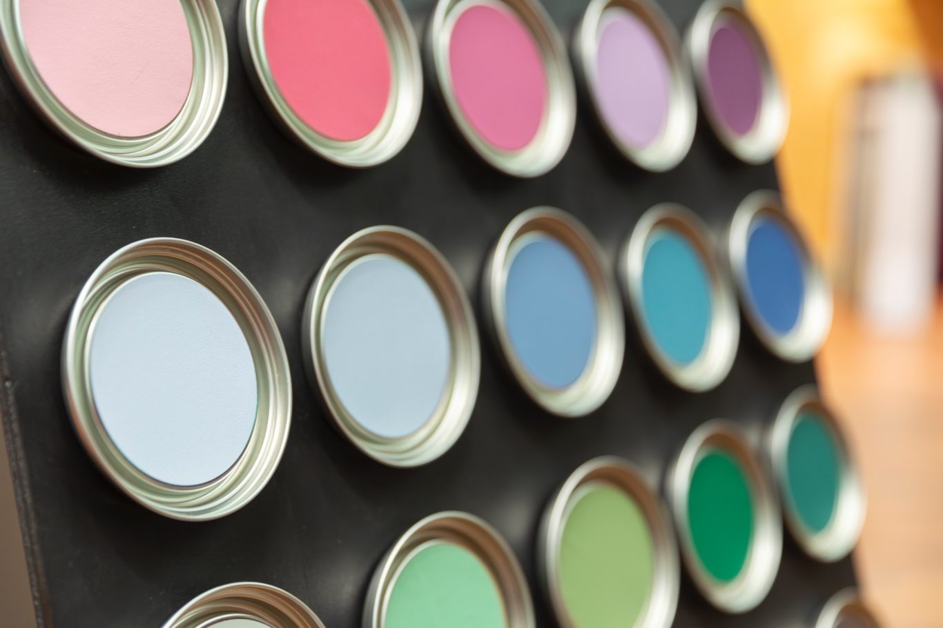 Farbige Lacke Farbige Lacke in Dosen, angeordnet in mehreren Reihen auf einer schwarzen Fläche.