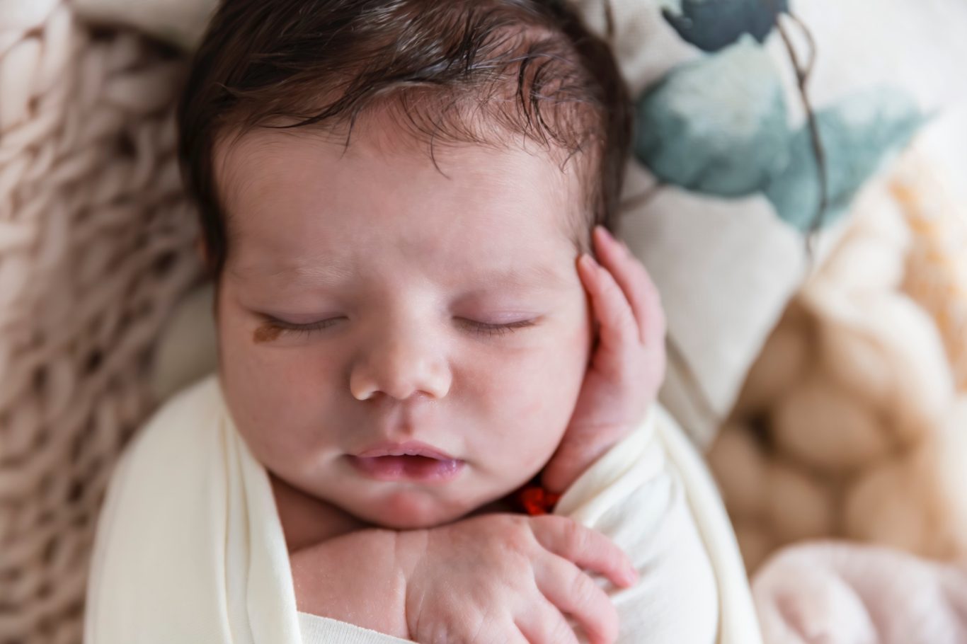 newbornshooting babyshooting GeistFrei Neugeborenes Baby schläft friedlich mit der Hand im Gesicht.