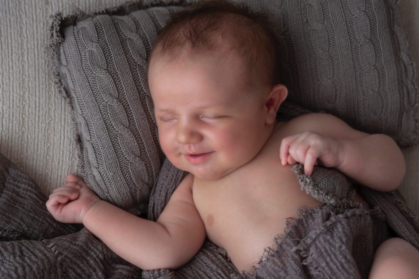 ein baby-lächeln babyfotografie GeistFrei! Schlafendes Baby mit einem glücklichen Gesichtsausdruck, eingekuschelt in Decken.