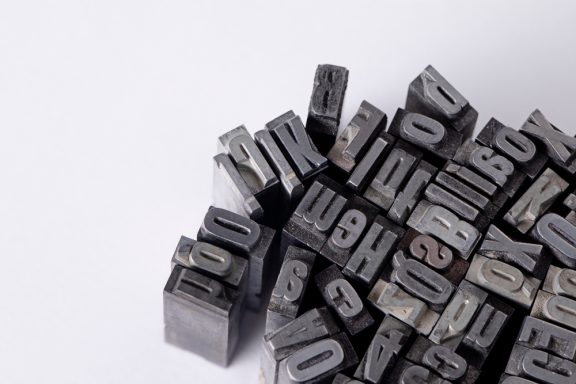 Zufällig angeordnete Buchstaben- und Zahlenstempel auf hellem Hintergrund.