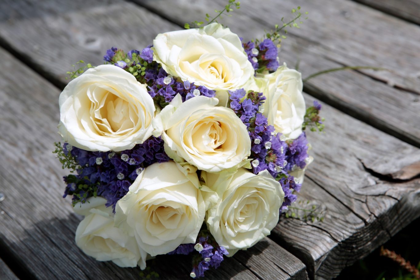 Brautstrauß GeistFrei! Ein Bouquet aus weißen Rosen und lila Blumen auf einer Holzoberfläche.
