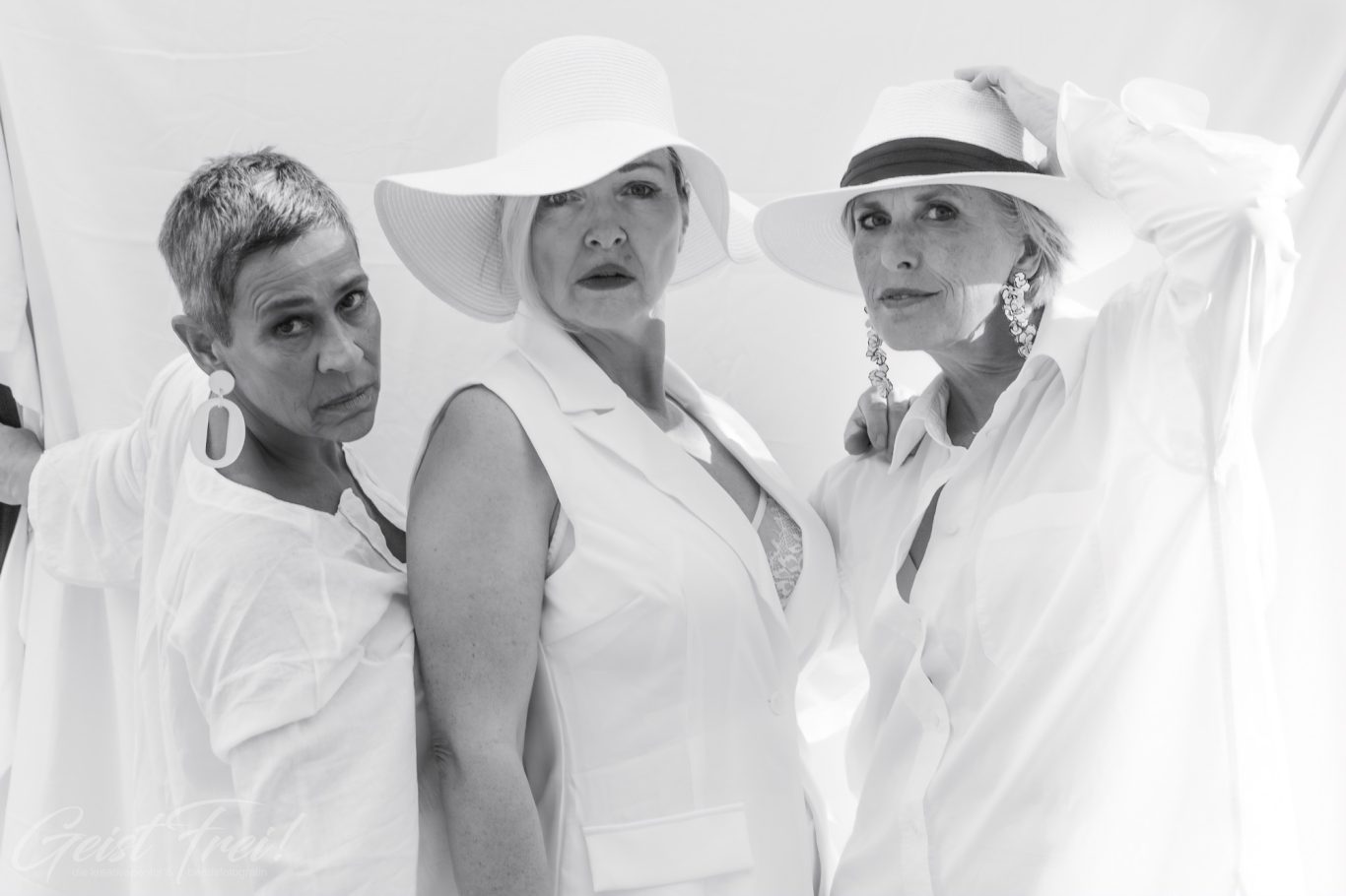 drei ladys in weiss Drei Frauen in weißen Hüten und blauen Outfits posieren auf einem hellen Hintergrund.