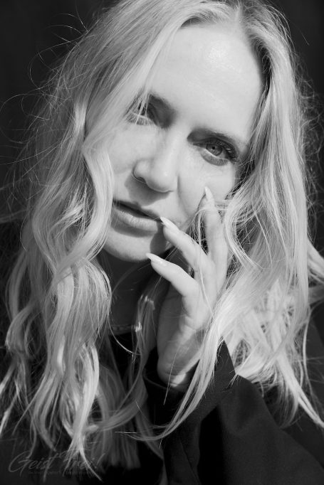 Porträt einer Frau mit langen, welligen Haaren, die nachdenklich schaut.