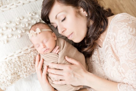 Eine Mutter hält eng ihr schlafendes Baby in sanfter Umarmung.