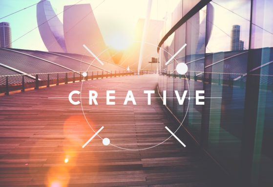 Holzsteeg mit dem Wort „CREATIVE“ und heller, verschwommener Hintergrund.