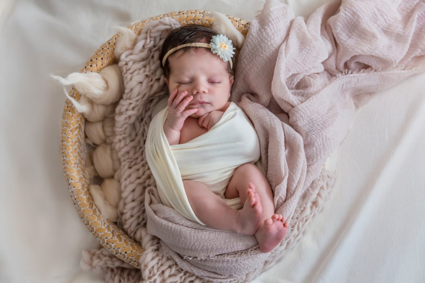 newbornshooting babyshooting GeistFrei Neugeborenes Baby, sanft eingewickelt in Decken, liegt in einem Korb.